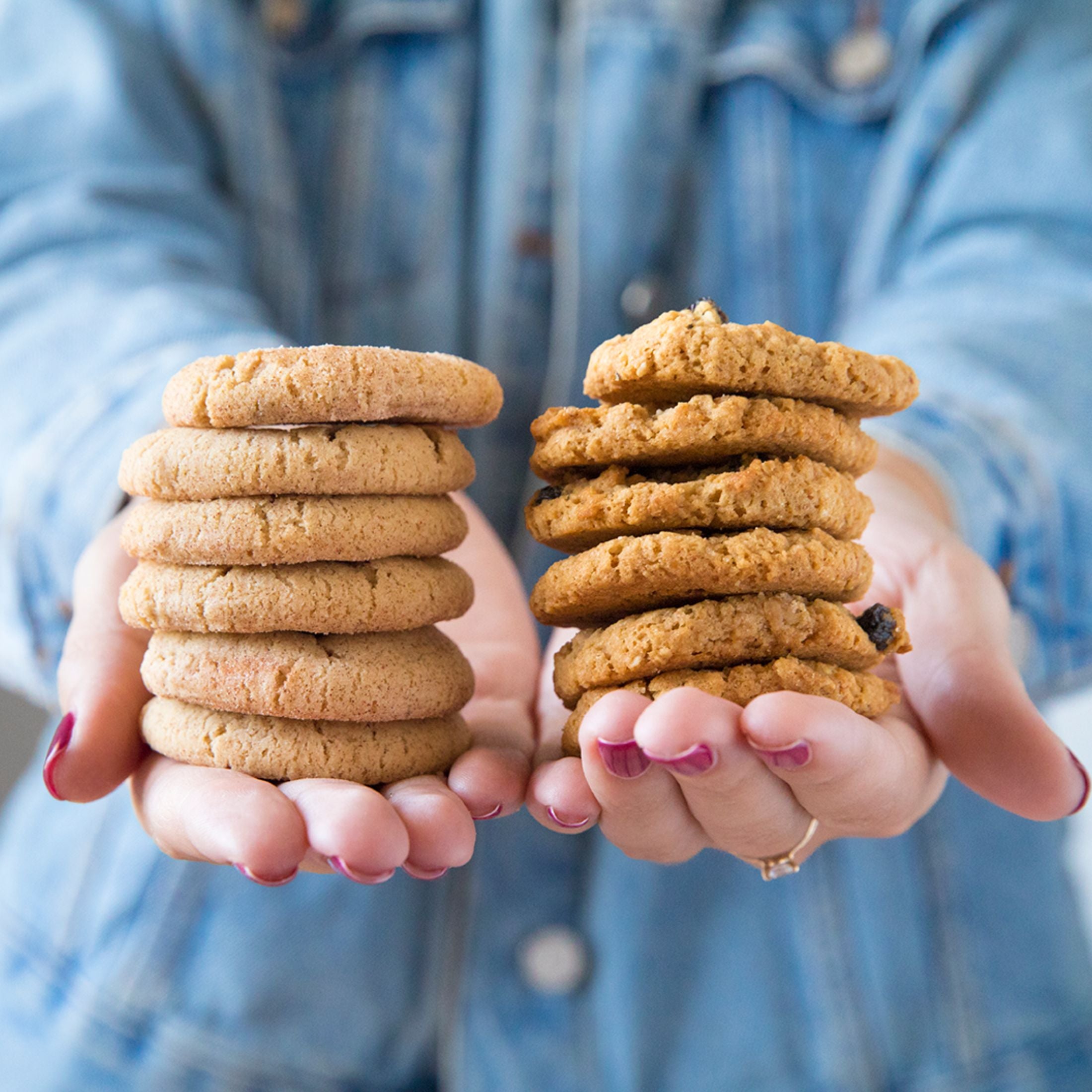 Models hands with two stacks of cookies. One stack of oatmeal raisin and one with snickerdoodle
