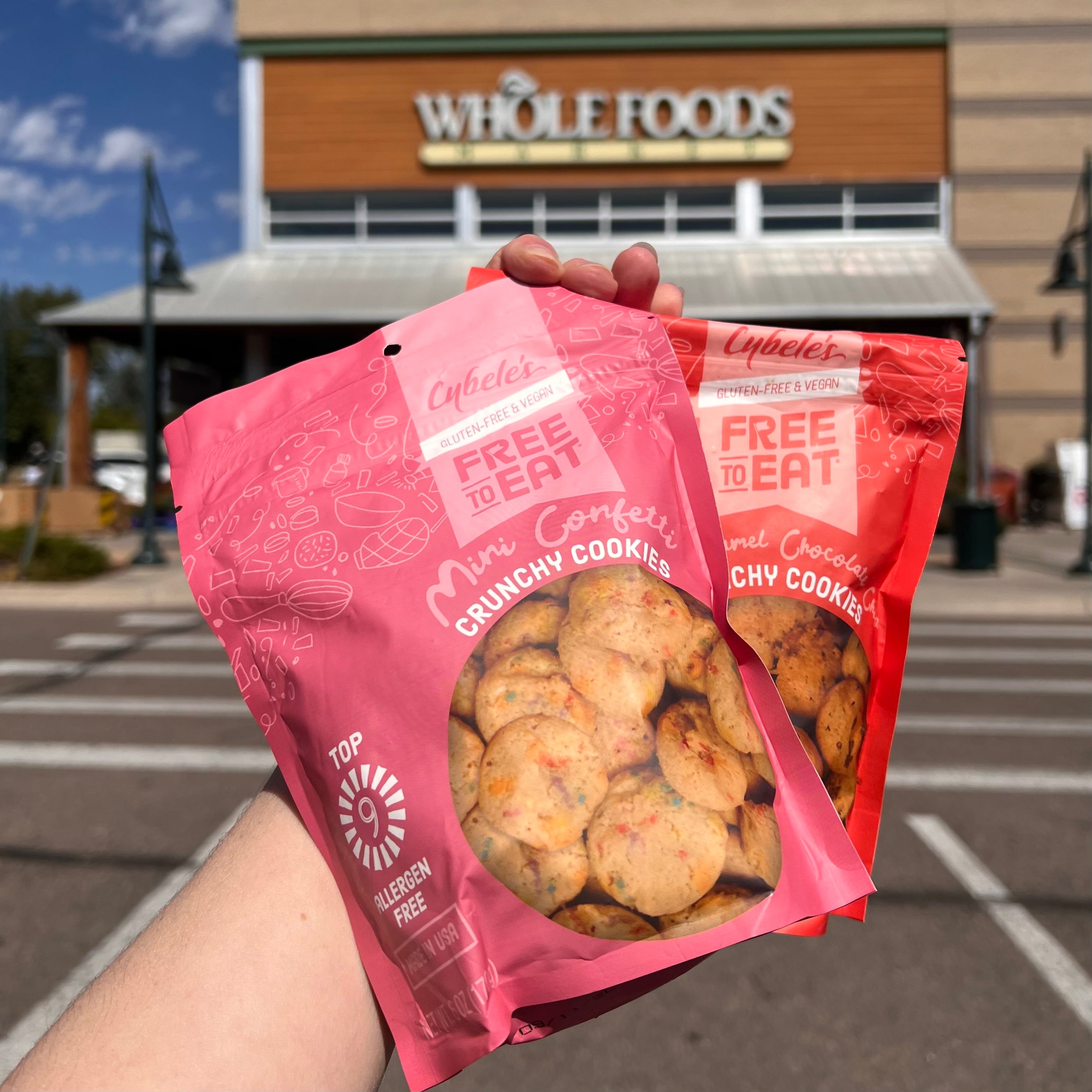 Woman's hands holding up Mini Confetti and Mini Caramel Chocolate Chips in front of Whole Foods entrance